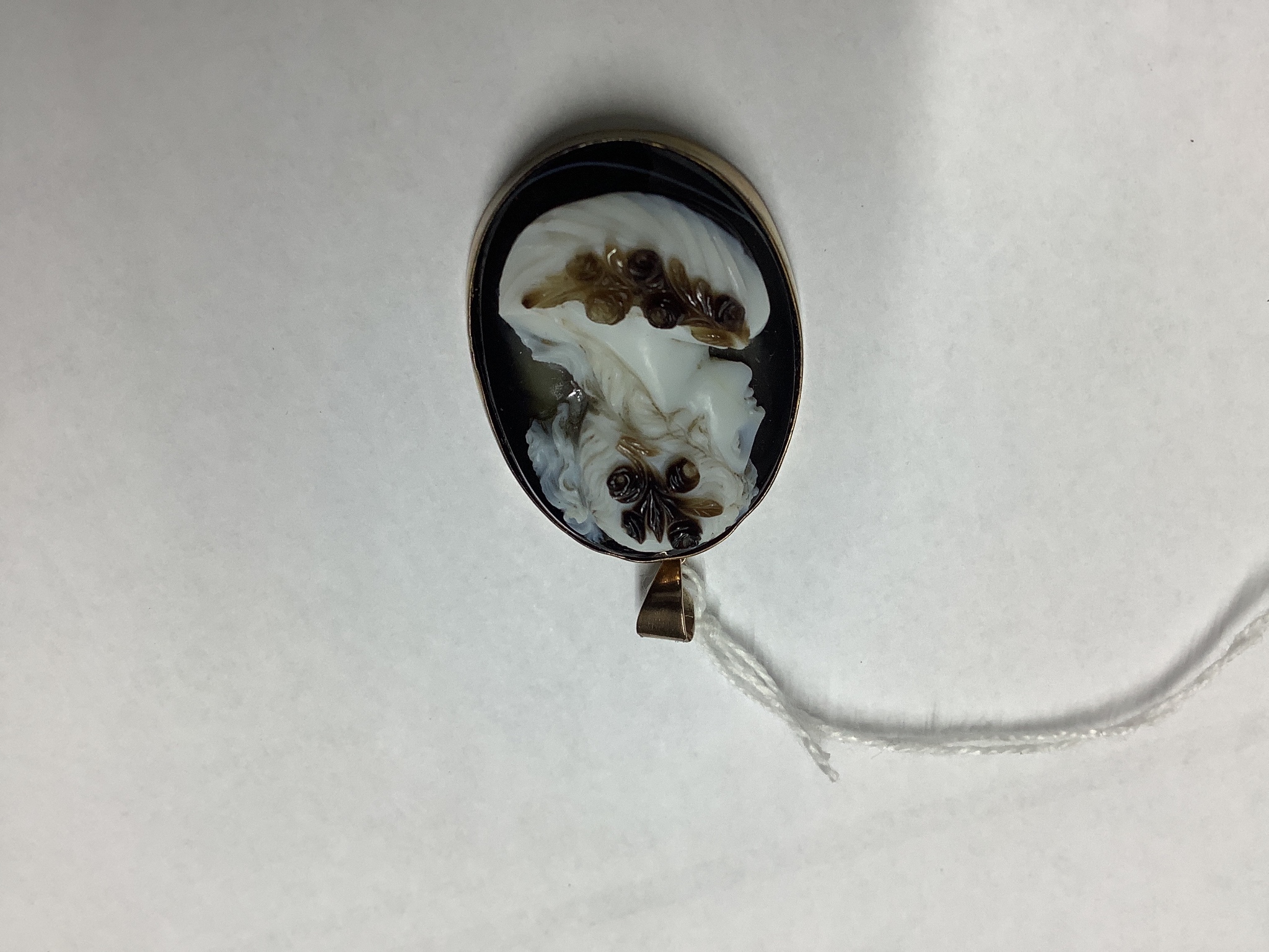 A late Victorian gilt metal mounted oval banded agate pendant, carved with the bust of a lady to dexter, agate length 35mm.